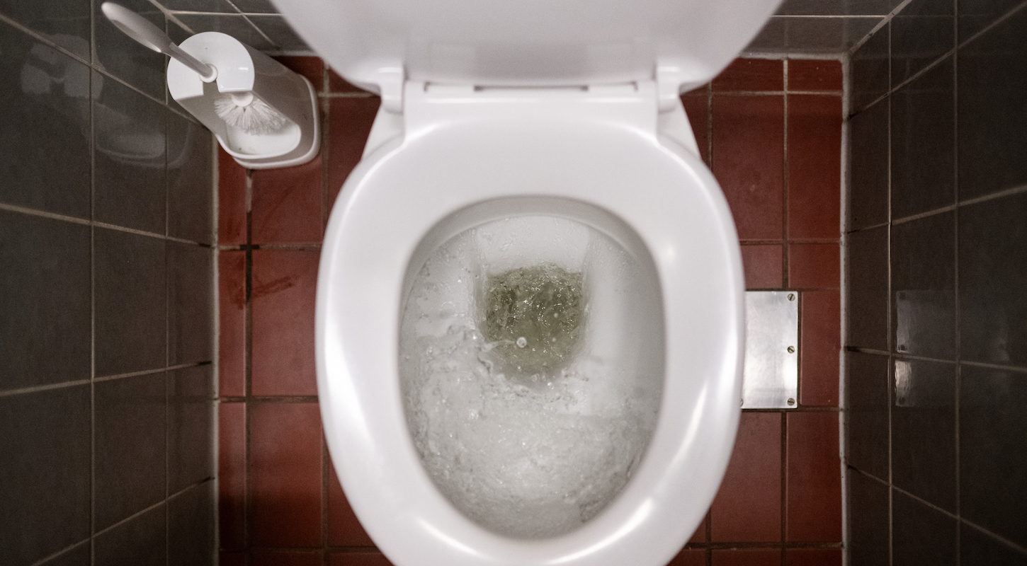 A toilet, viewed from above, mid-flush but thankfully with nothing but clear water in it.