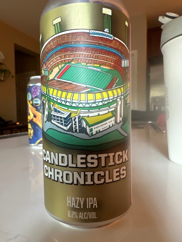 A photograph of a can of the Candlestick Chronicles Hazy IPA from Cooperage Brewing. It's got a colorful  illustration of the old football field and notes that it's 6.2% ABV.