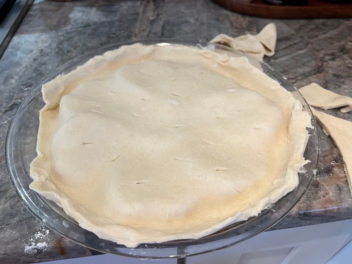 A sheet of raw pastry dough draped over the pears, pierced with a knife and tucked in around the edges.