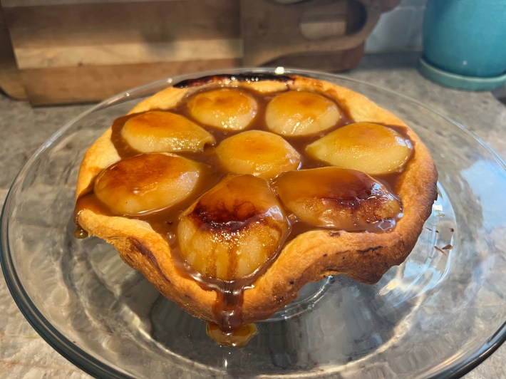 A side view of a finished tarte tatin, showing a small overflow of caramel.