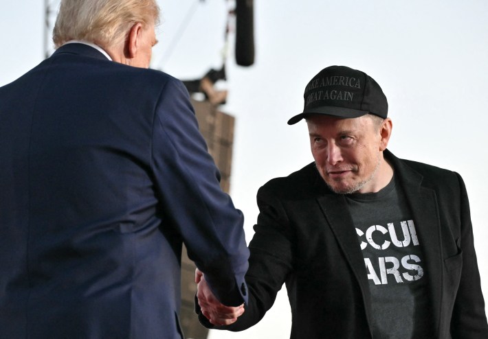 Elon Musk joins former US President and Republican presidential candidate Donald Trump during a campaign rally at the site of his first assassination attempt in Butler, Pennsylvania on October 5, 2024. Musk is looking at them like private piles in full metal jacket.