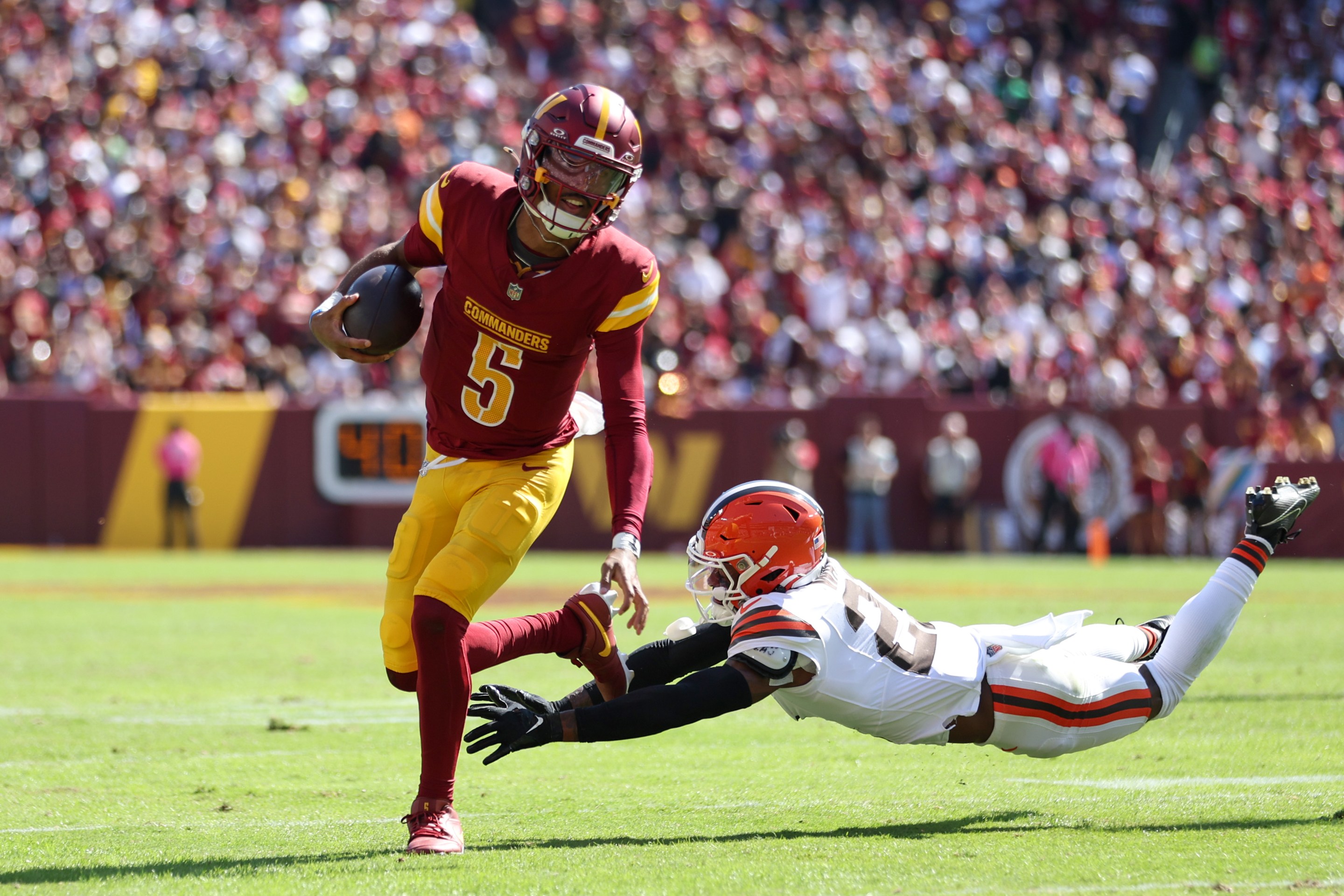 Jayden Daniels #5 of the Washington Commanders runs the ball as Denzel Ward #21 of the Cleveland Browns attempts to tackle during the first half at FedExField on October 06, 2024 in Landover, Maryland.