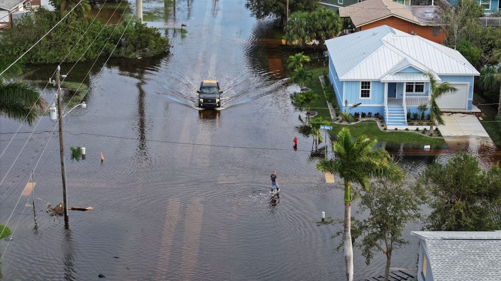 In this aerial view, a person walks through flood waters that inundated a neighborhood after Hurricane Milton came ashore on October 10, 2024, in Punta Gorda, Florida. The storm made landfall as a Category 3 hurricane in the Siesta Key area of Florida, causing damage and flooding throughout Central Florida.