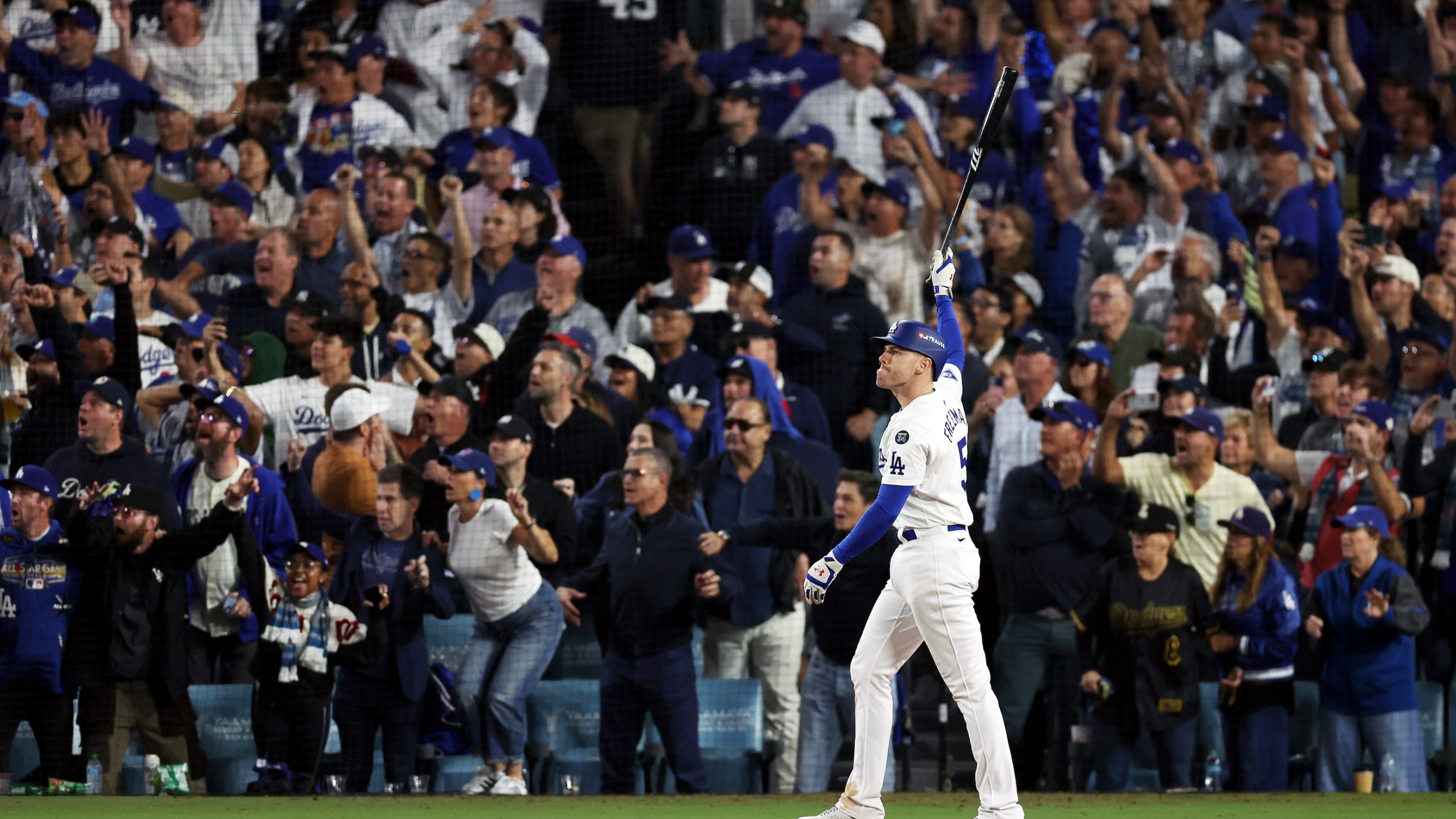 Freddie Freeman points his bat at the sky in the foreground while various Dodgers fans watch his game-winning grand slam home run and freak out in the background. This was from Game 1 of the 2024 World Series, at Dodgers Stadium.