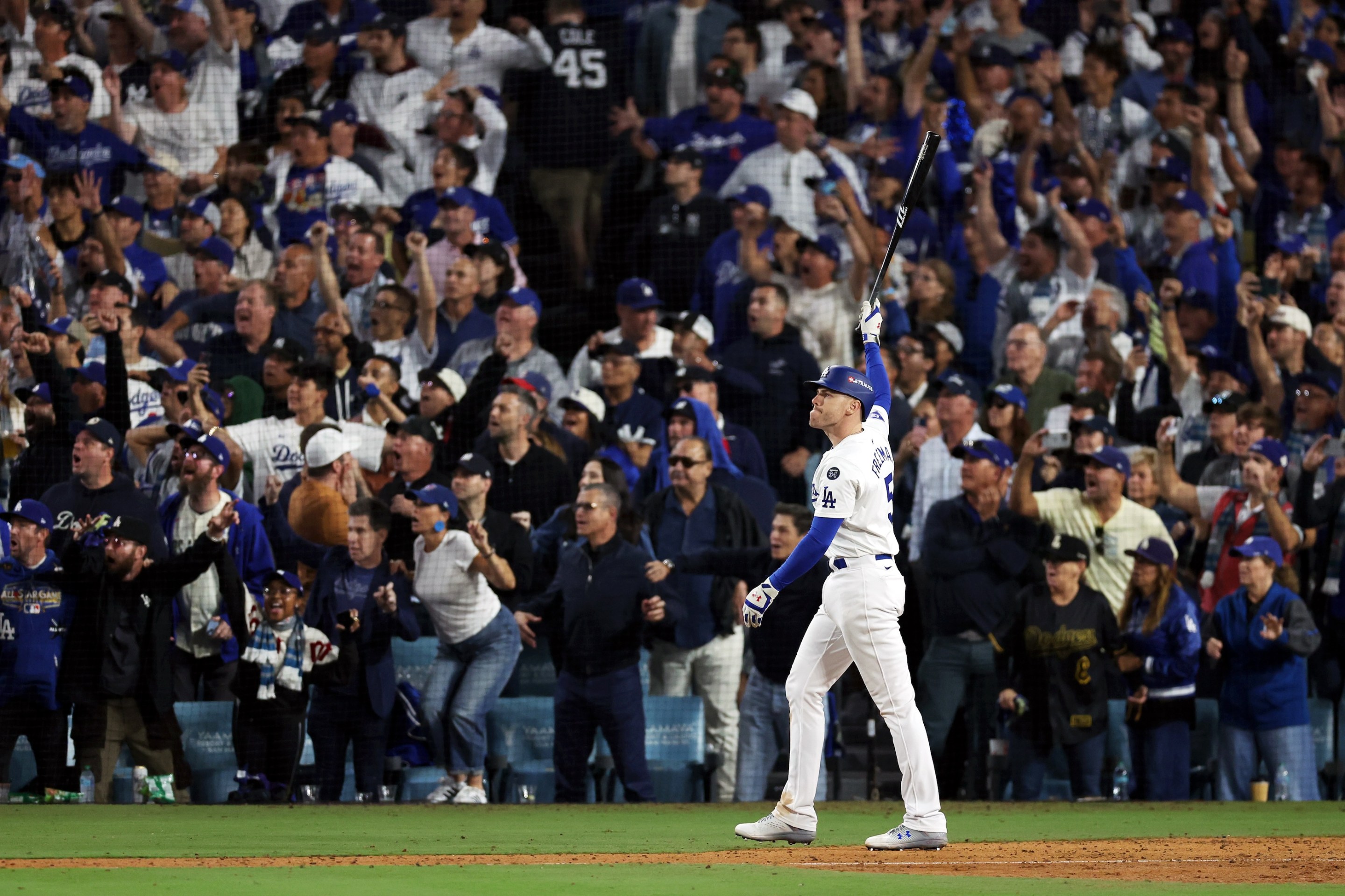 Freddie Freeman points his bat at the sky in the foreground while various Dodgers fans watch his game-winning grand slam home run and freak out in the background. This was from Game 1 of the 2024 World Series, at Dodgers Stadium.