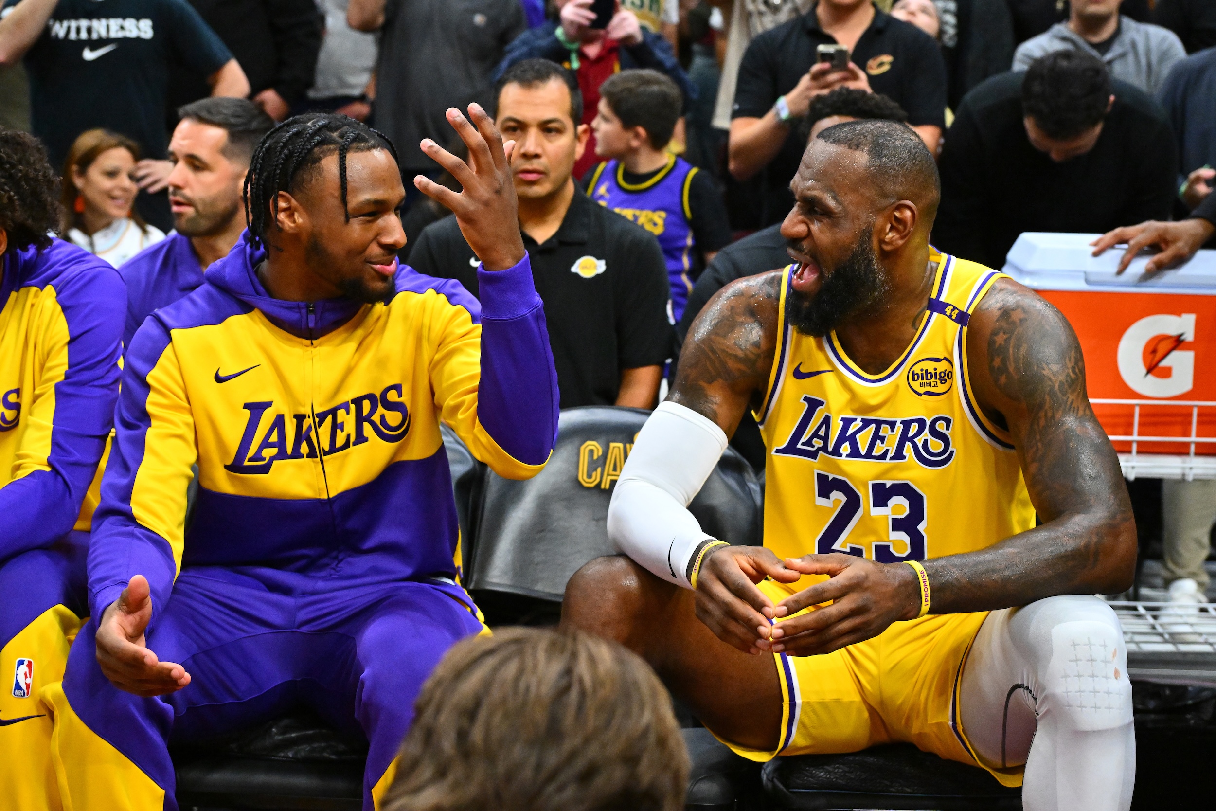 Bronny James talks with LeBron James of the Los Angeles Lakers on the bench during the first half against the Cleveland Cavaliers.