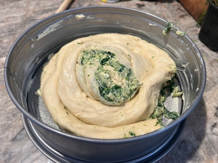 A raw half-exploded spiral of spanakopita.