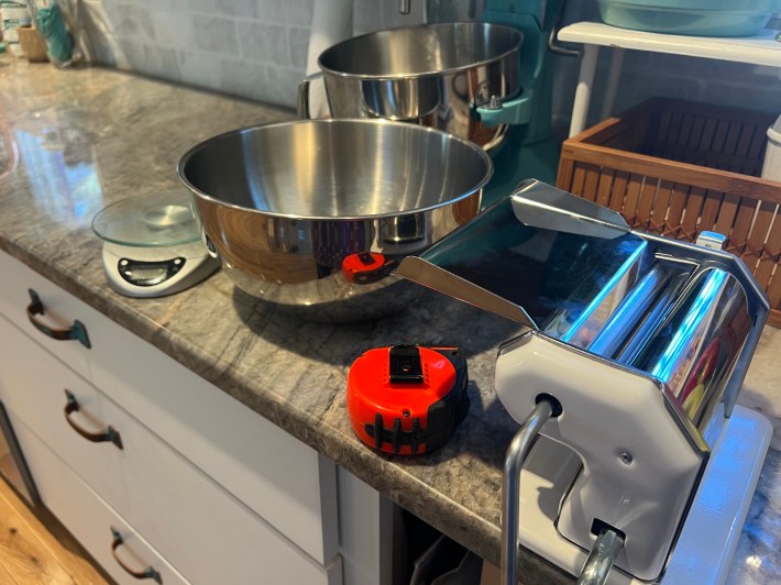 Kitchen scale, mixing bowl, tape measure, and pasta maker.