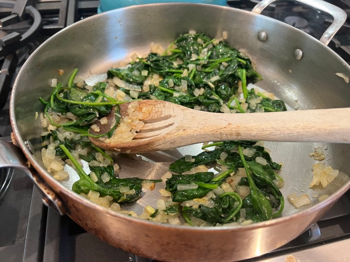 Spinach, onions, and garlic in a sauté pan.