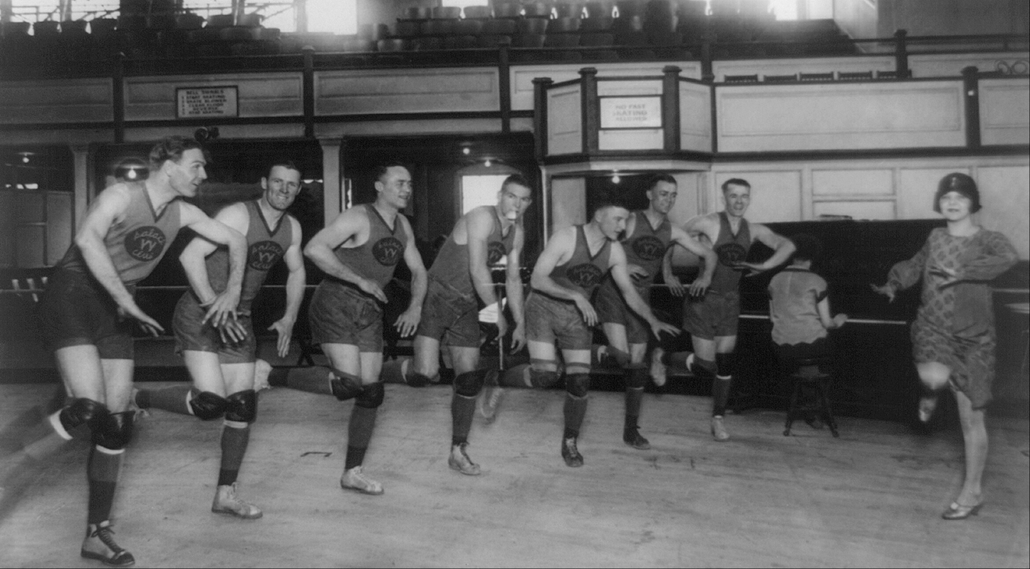 A circa-1900 black-and-white photo of basketball players receiving dance lessons from a lady in a flapper hat and dress.