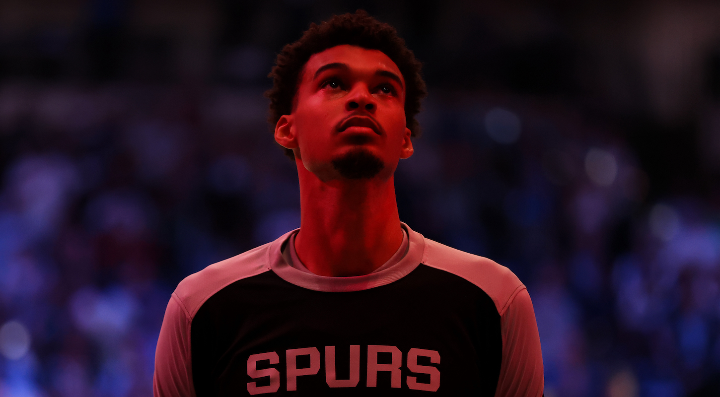 Victor Wembanyama of the San Antonio Spurs, illuminated by somewhat spooky crimson light during the pregame ceremonies ahead of Thursday night's road game against the Dallas Mavericks.