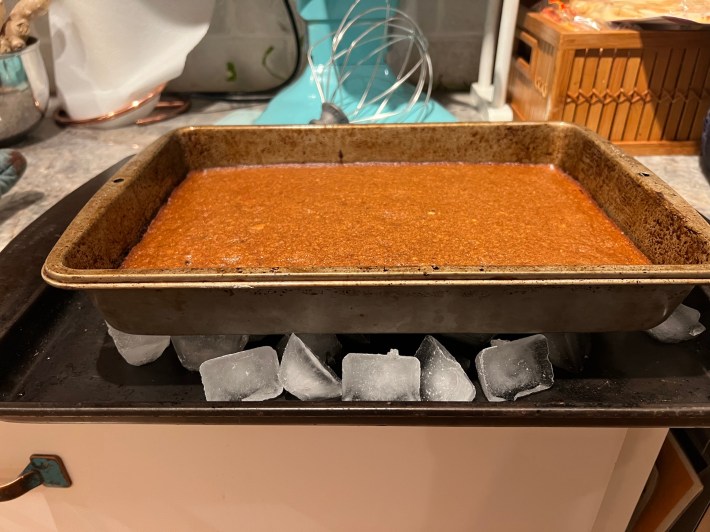 A baked Parkin, still in the baking pan, resting on a bed of ice.