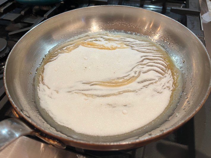 Caster sugar begins to caramelize in a pan.