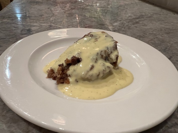 A slice of Spotted Dick, covered with créme anglaise.