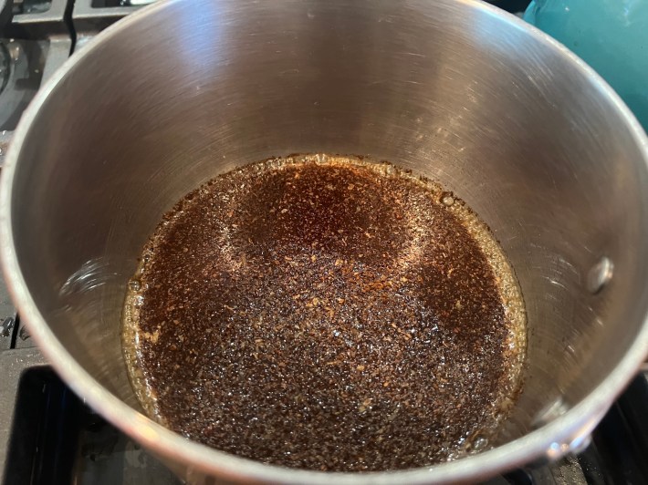 Coffee grounds, water, and sugar simmer together in a saucepan.