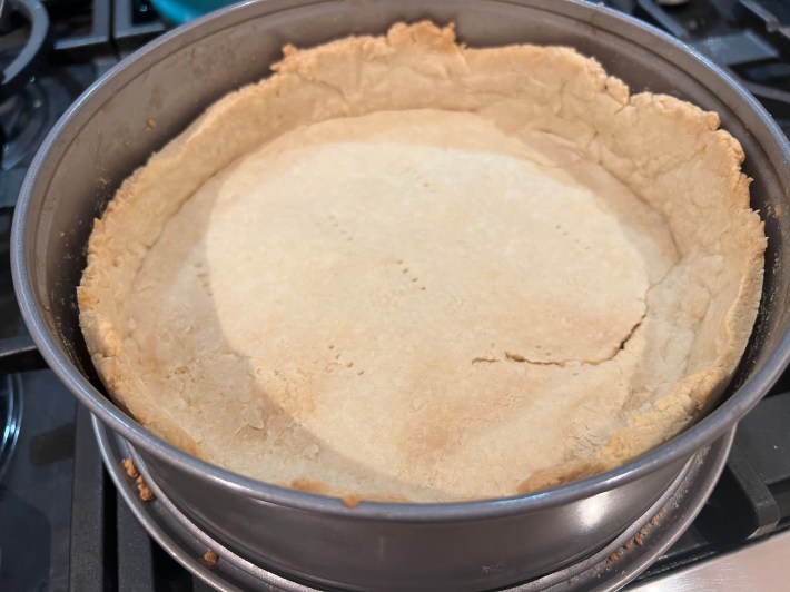 A baked pie crust with a large crack along the bottom.