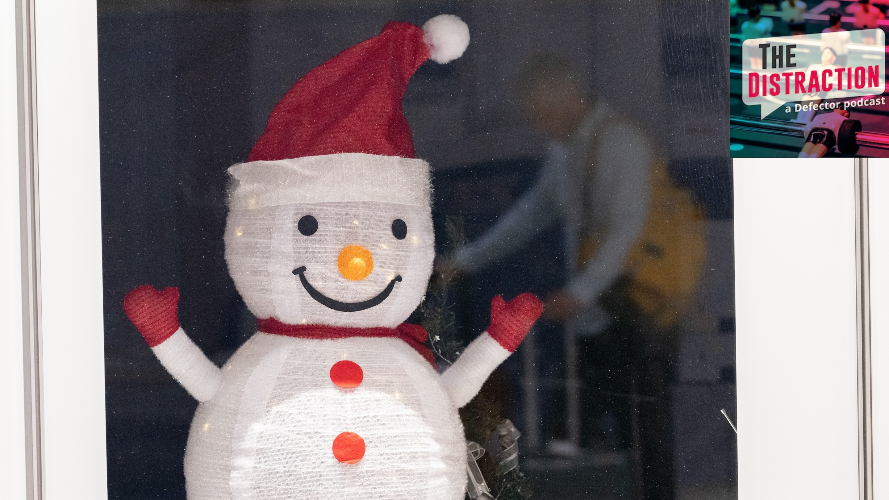 A traveler is reflected in a pane of glass with a paper snowman behind it during travel on Christmas Day at Frankfurt Airport.
