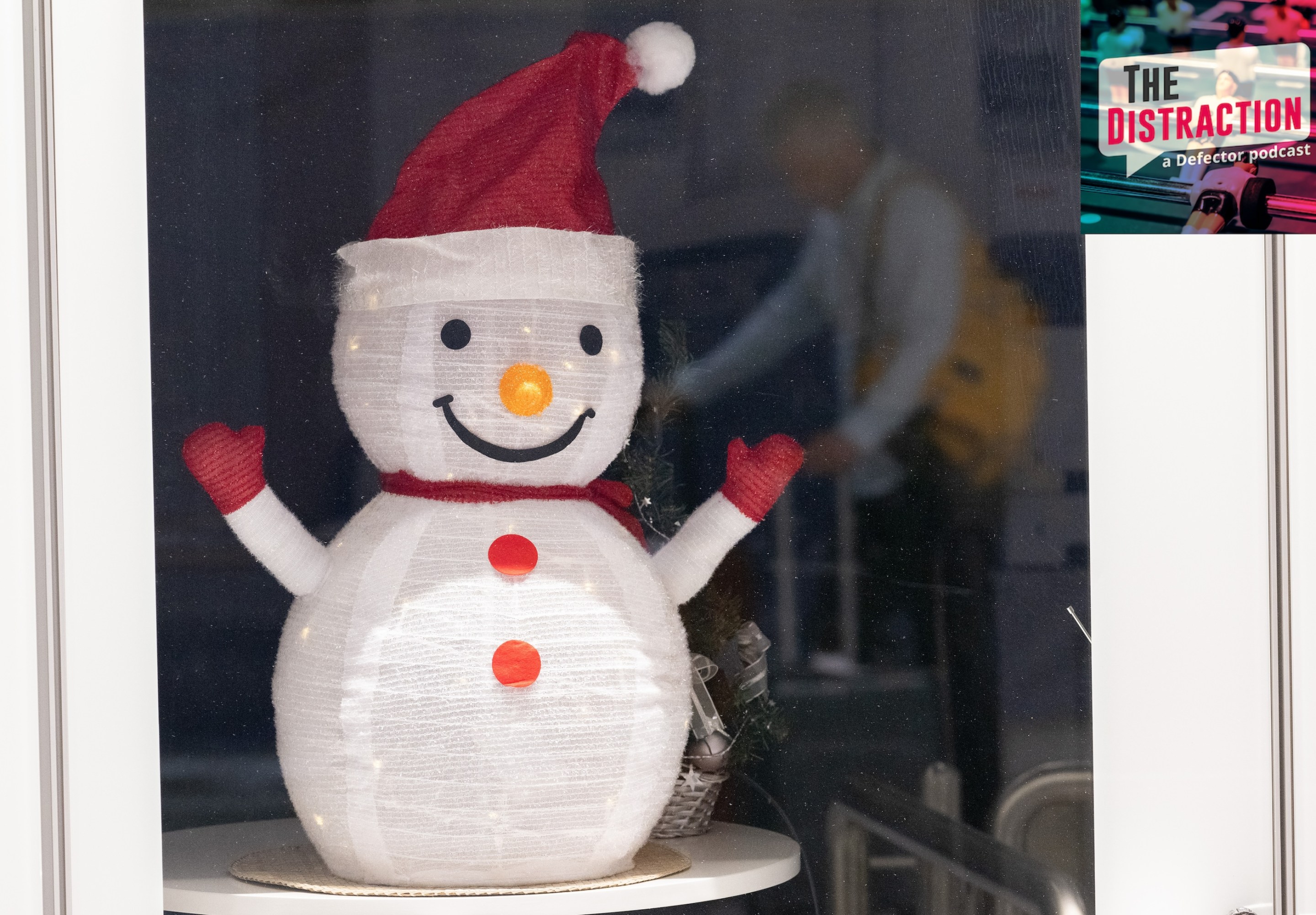 A traveler is reflected in a pane of glass with a paper snowman behind it during travel on Christmas Day at Frankfurt Airport.