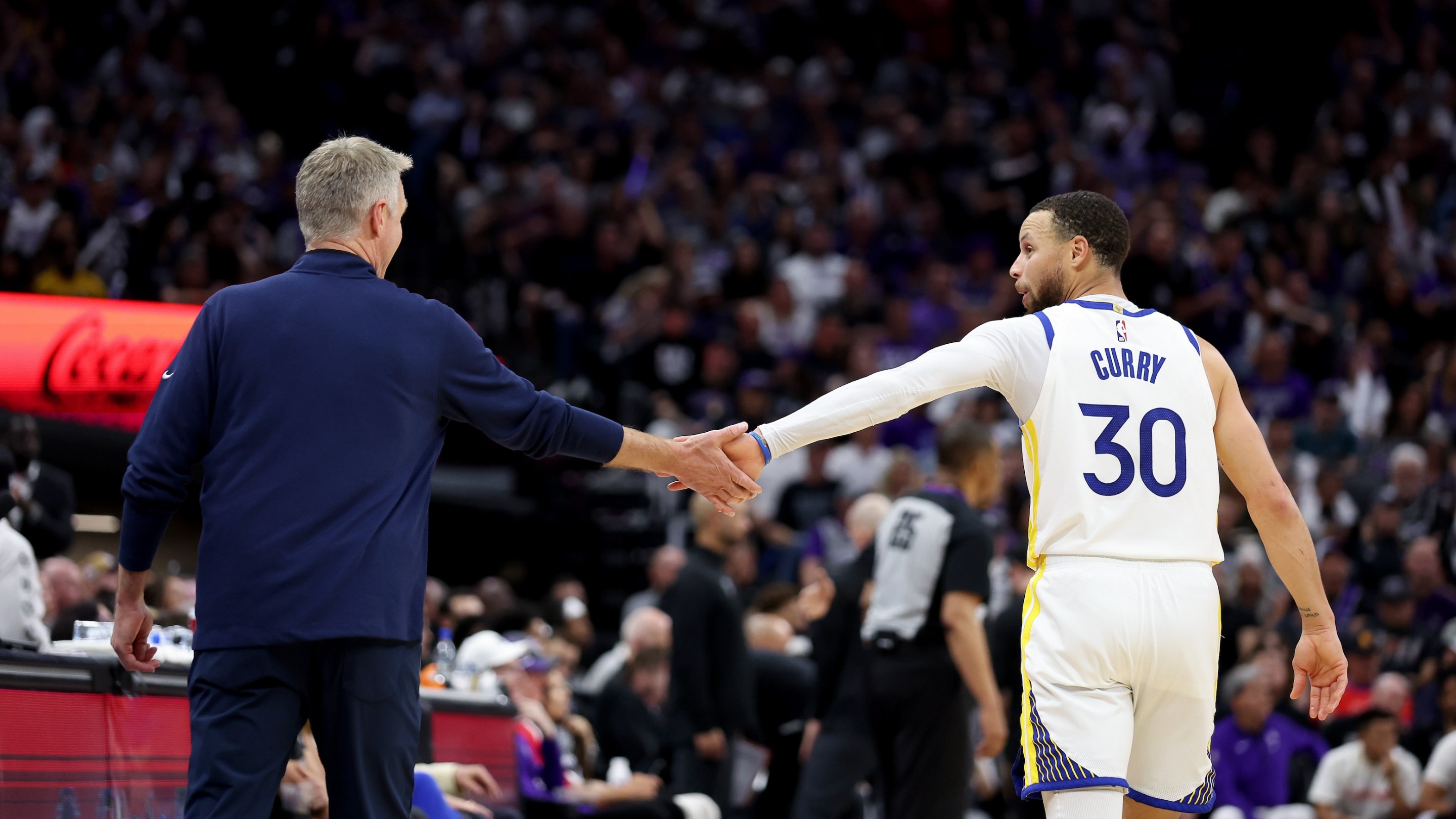 Stephen Curry (right) and Steve Kerr (left) high-five during an April 26, 2023 Warriors game against the Sacramento Kings.