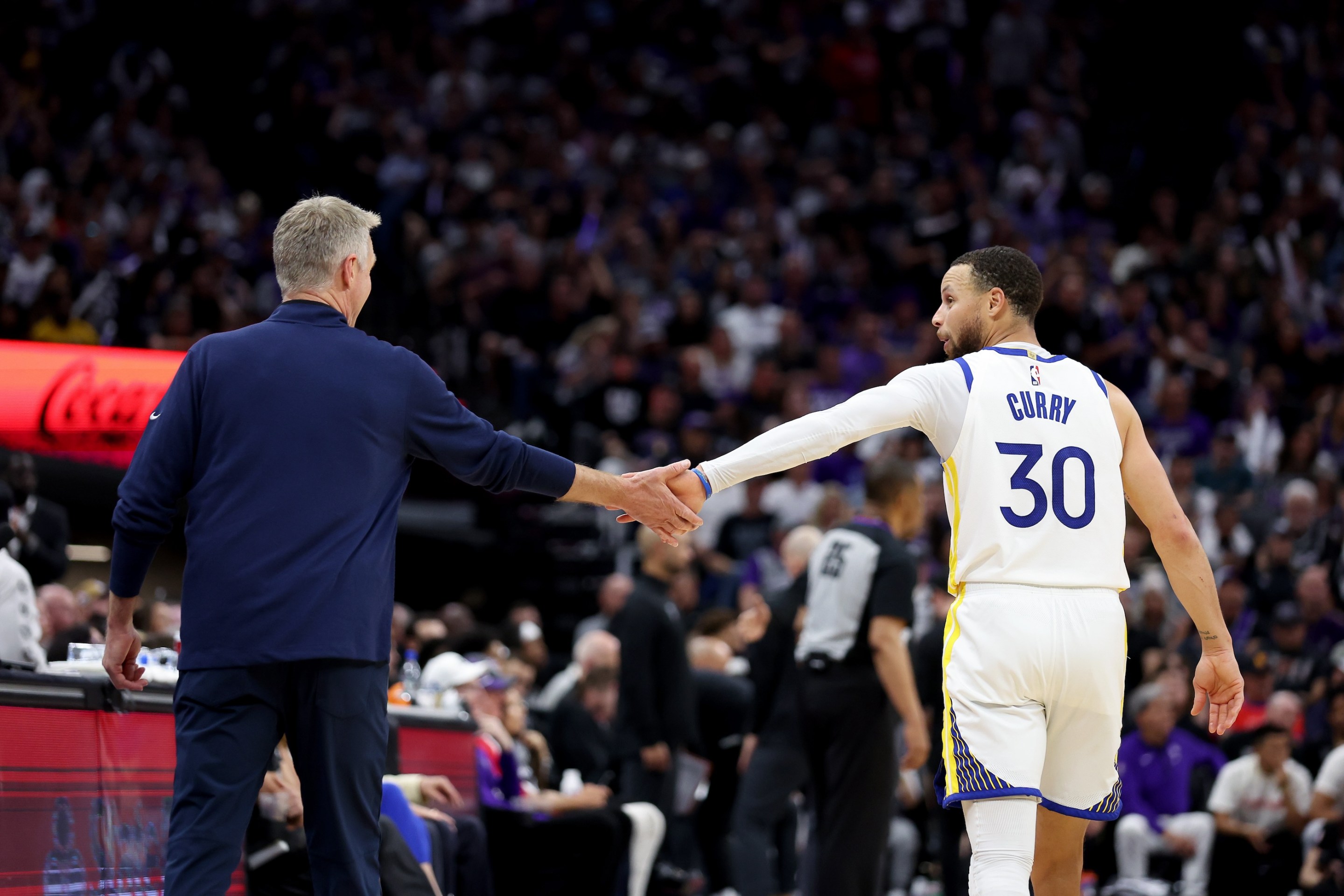 Stephen Curry (right) and Steve Kerr (left) high-five during an April 26, 2023 Warriors game against the Sacramento Kings.