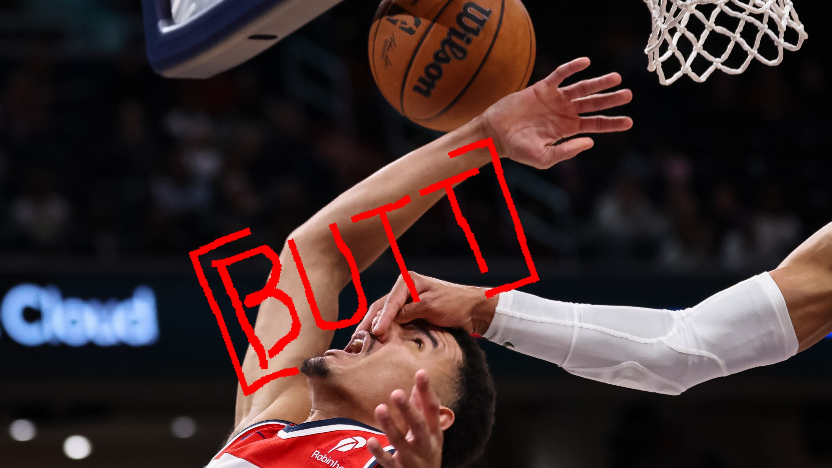 Johnny Davis of the Wizards, flailing at the basketball while being struck in the face, with the word "BUTT" superimposed over his arm.