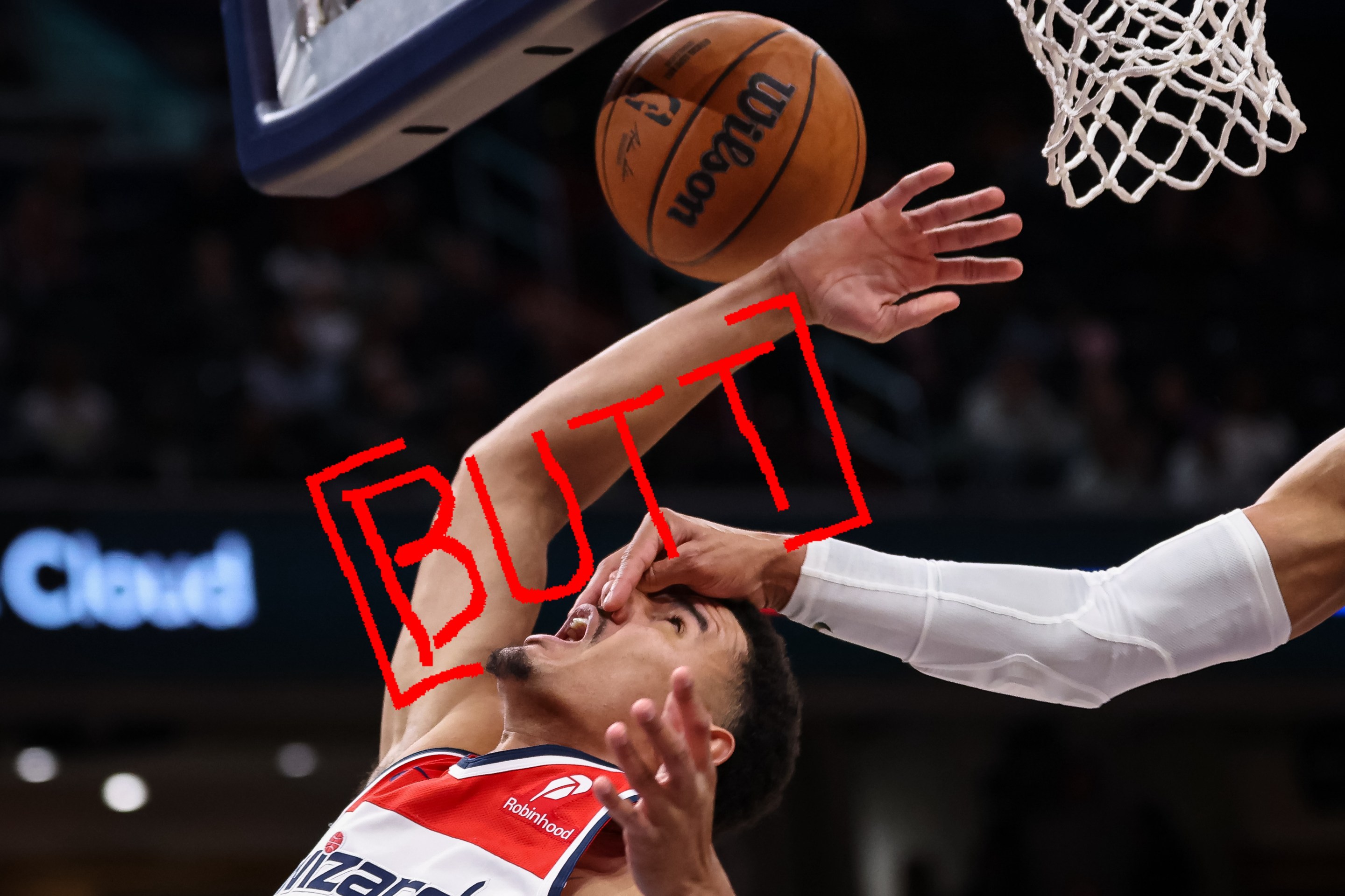 Johnny Davis of the Wizards, flailing at the basketball while being struck in the face, with the word "BUTT" superimposed over his arm.