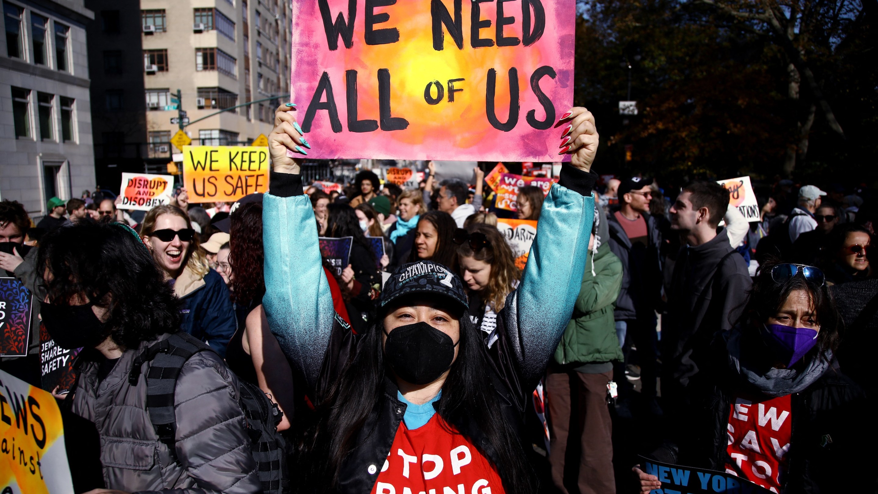 A detractor of president-elect Donald Trump protests against his policies in New York City on November 9, 2024. Their sign says "we need all of us."