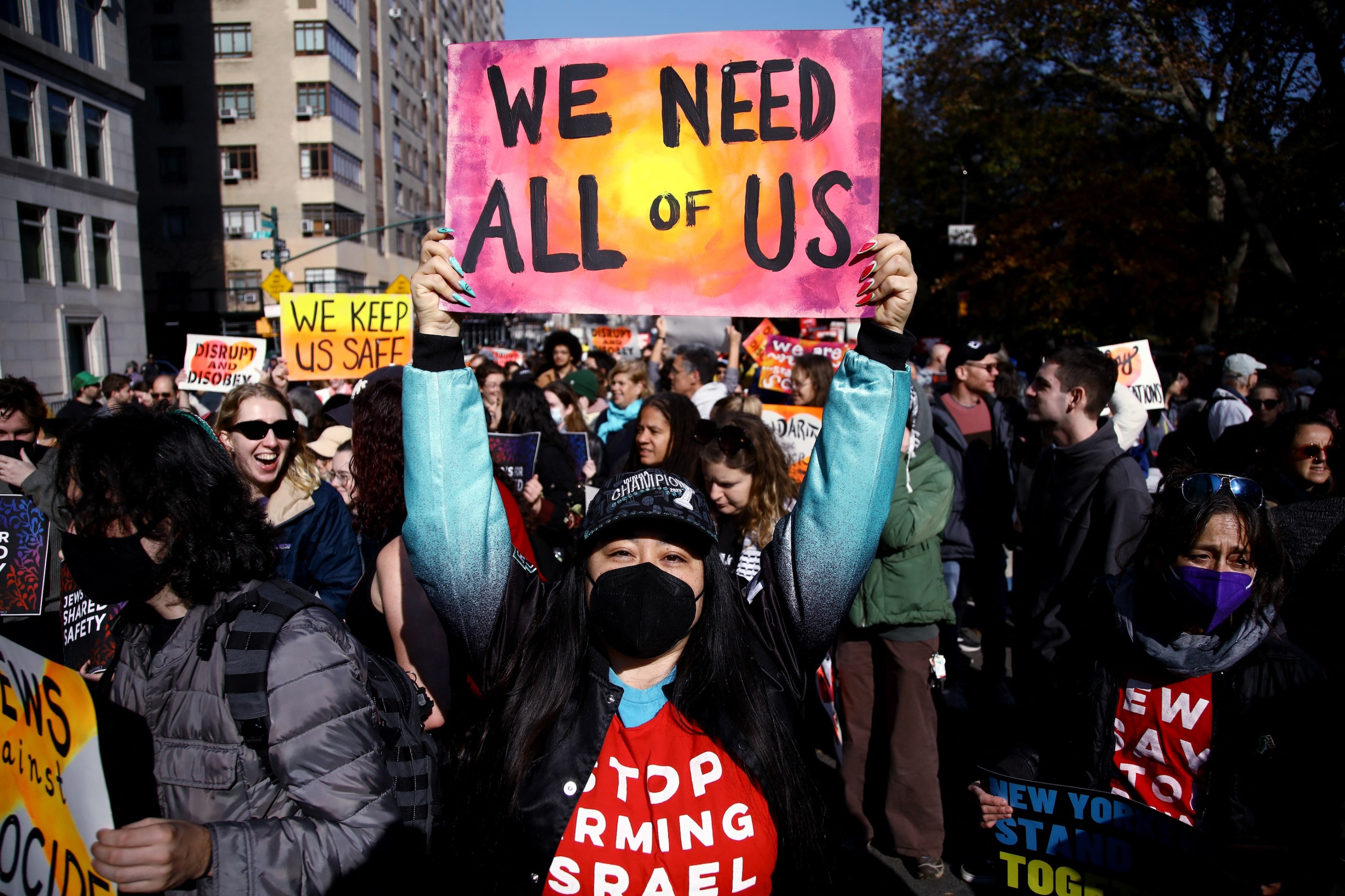 A detractor of president-elect Donald Trump protests against his policies in New York City on November 9, 2024. Their sign says "we need all of us."