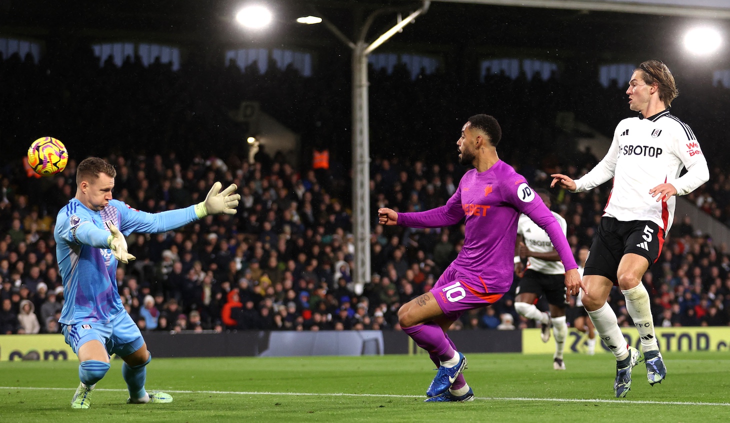 Matheus Cunha of Wolverhampton Wanderers scores his team's first goal whilst under pressure from Joachim Andersen of Fulham during the Premier League match between Fulham FC and Wolverhampton Wanderers FC at Craven Cottage on November 23, 2024 in London, England.