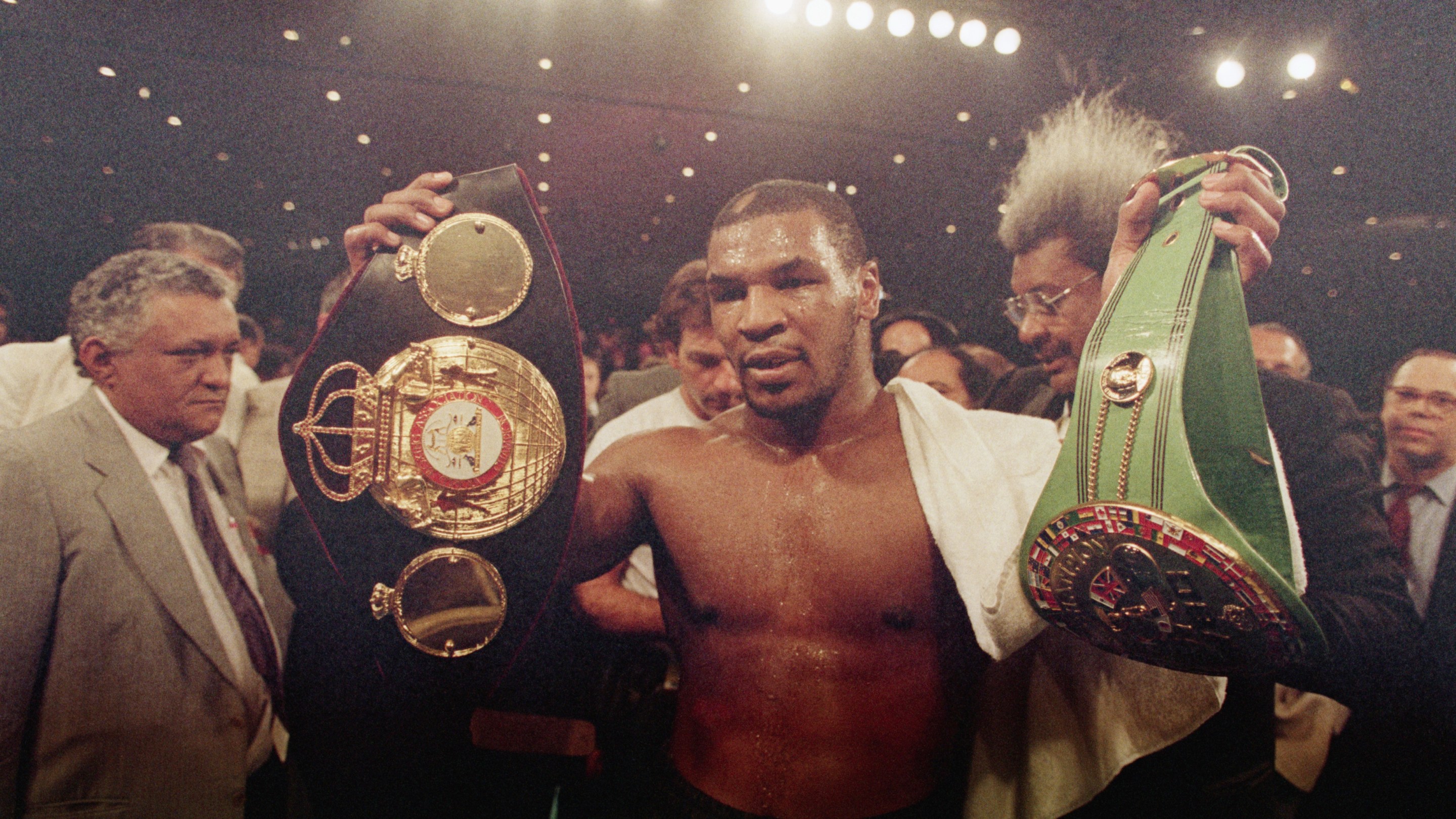 Mike Tyson holding his championship titles in the ring