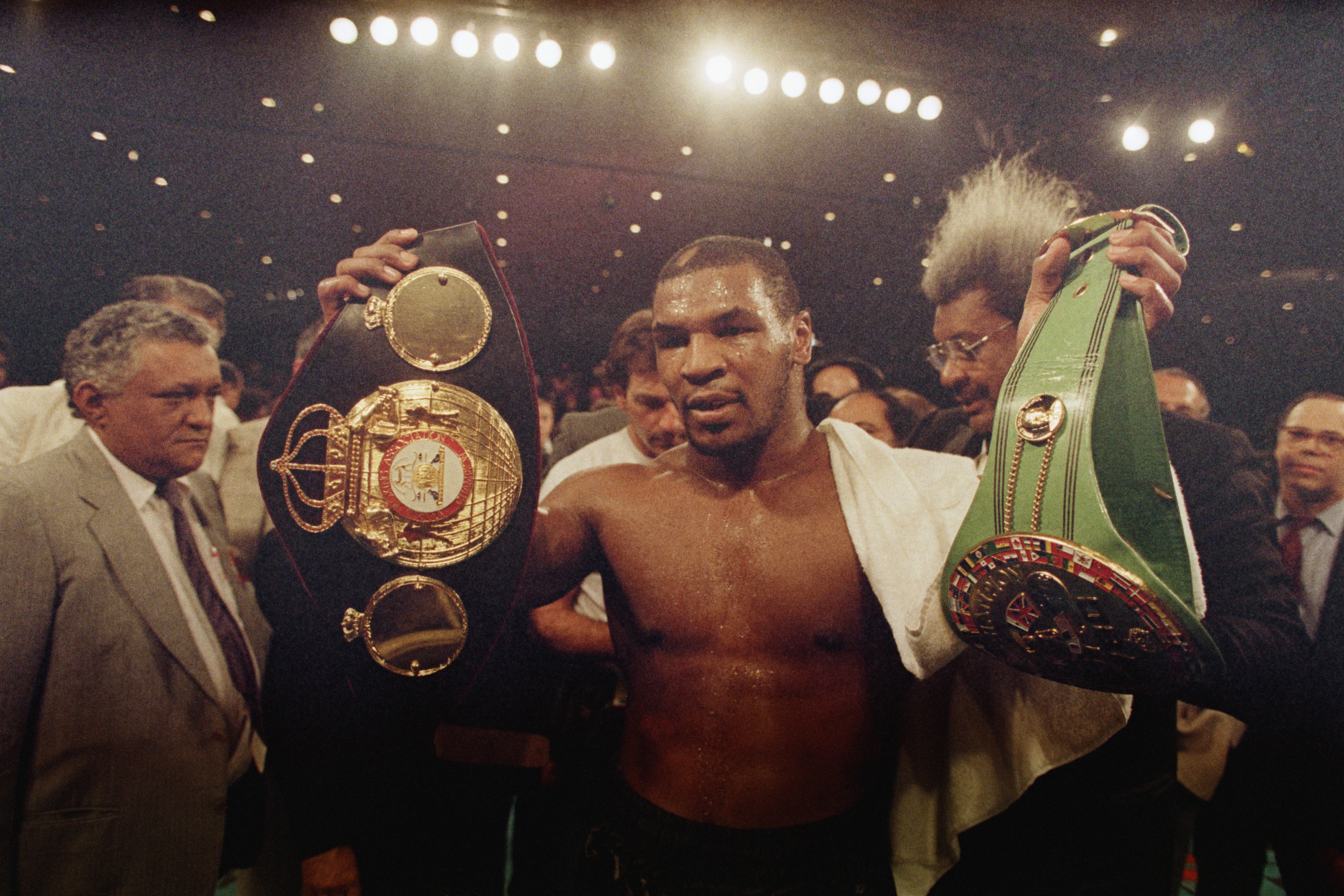Mike Tyson holding his championship titles in the ring