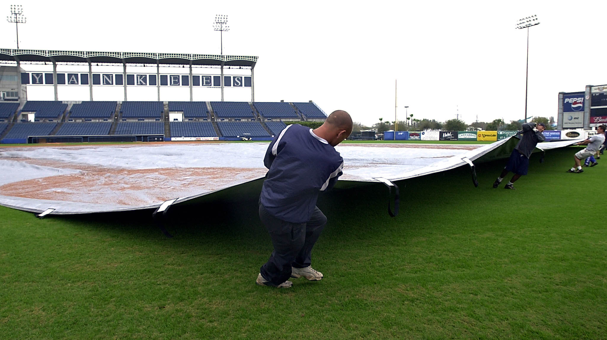 Field workers at the New York Yankees spring training camp pull a tarp across the field during a rain delay in 2022.