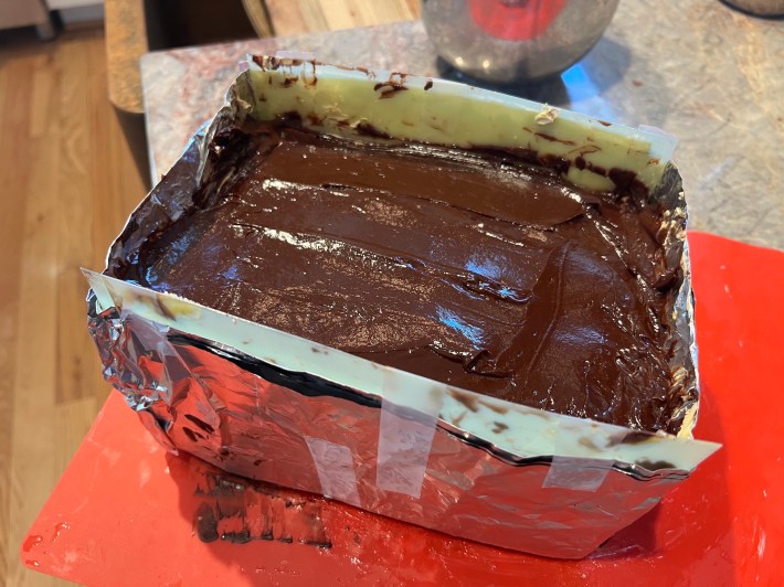 Chocolate glaze atop the cake stack inside the makeshift cake frame.