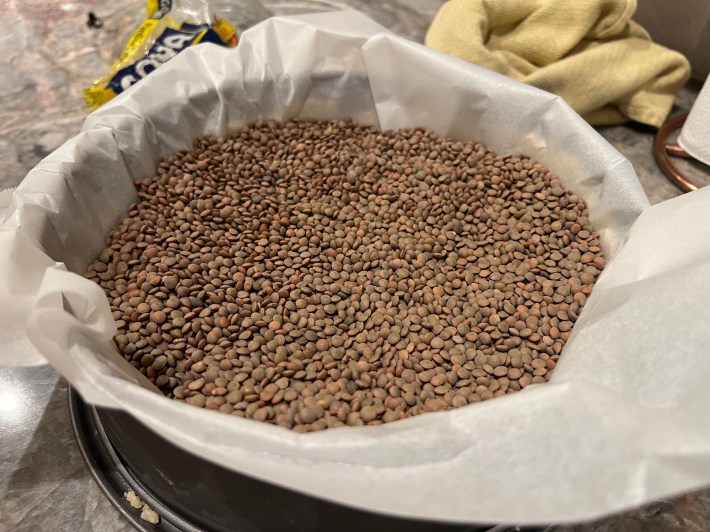 Parchment and lentils stuffed into a tart pan.