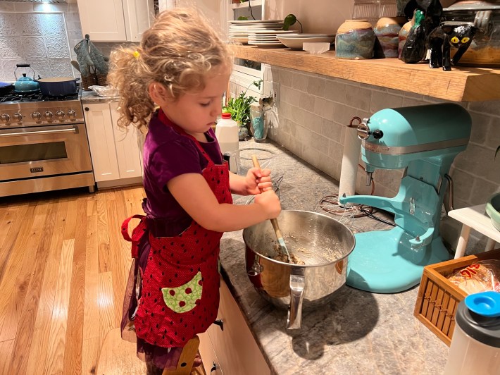 A child stirring batter with a rubber spatula.