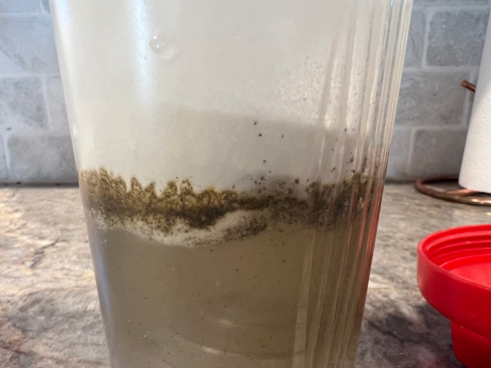 White protein powder sitting in a pile on top of water, inside a shaker bottle.