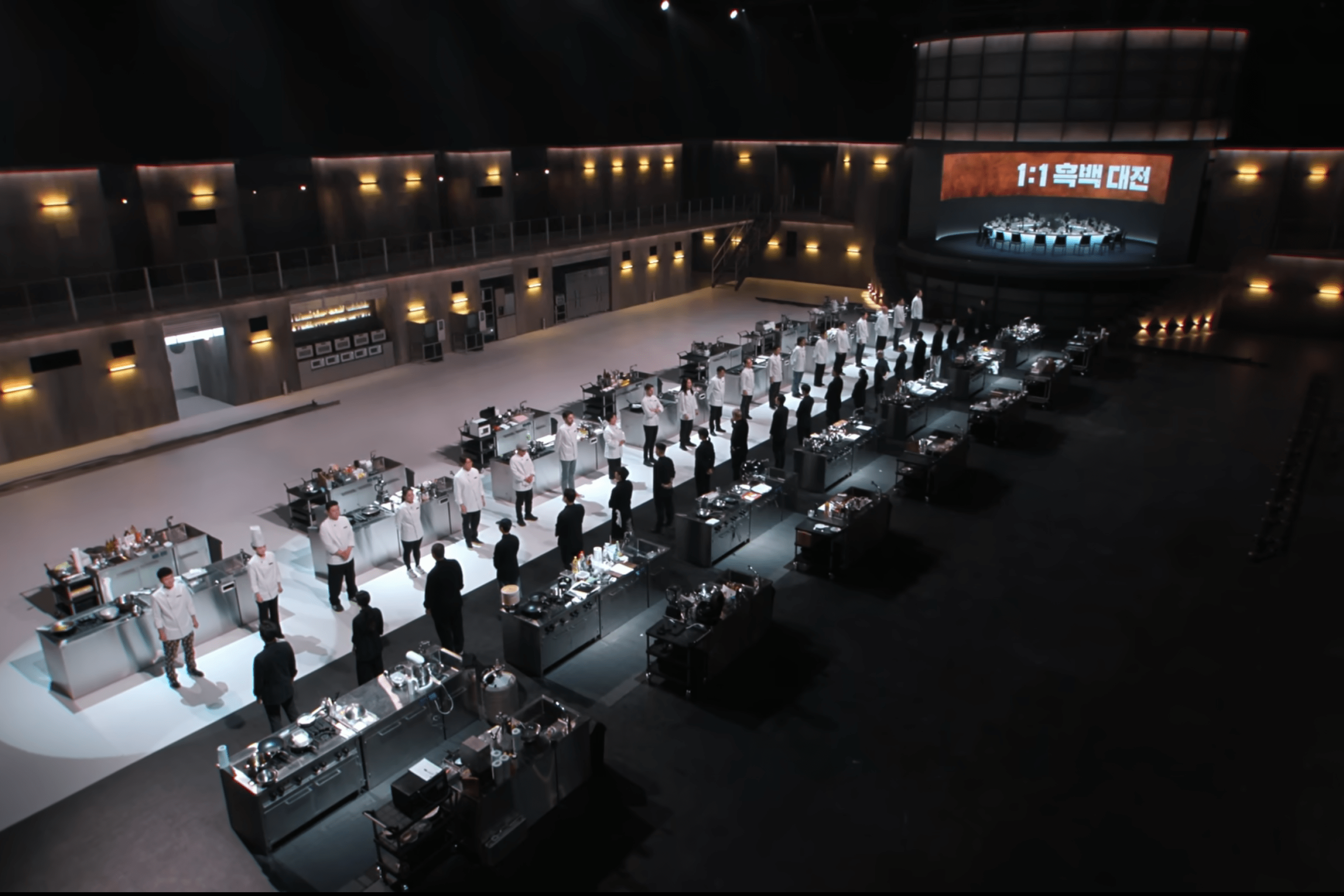 A cooking arena is divided into two sides: one black and one white. On each side there are ten chefs facing the other side.