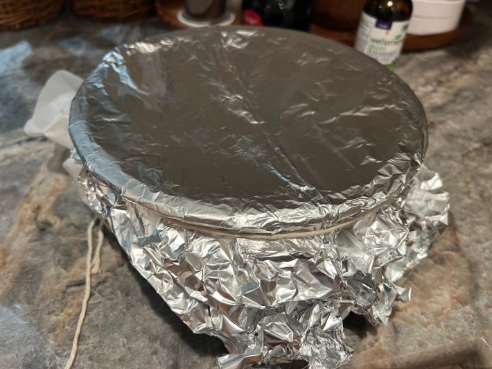 Parchment paper and foil, tied to form a lid on the bowl.