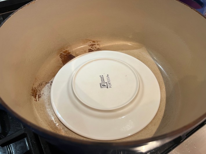 A side plate, upside down in the bottom of a dutch oven.