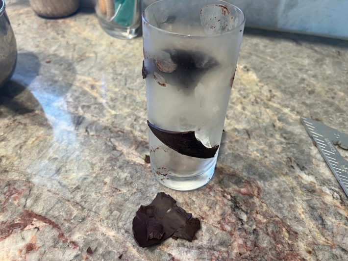 Frozen chocolate blobs cling to the sides of a drinking glass.