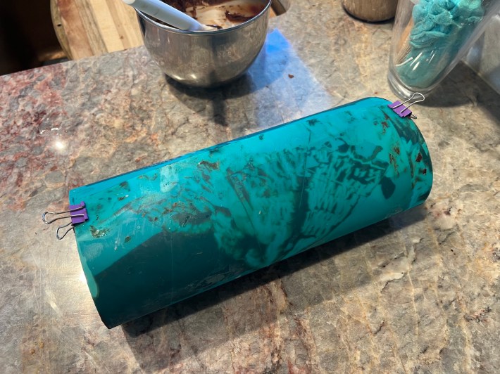 A blue plastic sheet rolled into a tube and held with clips. The inside is coated with melted chocolate.