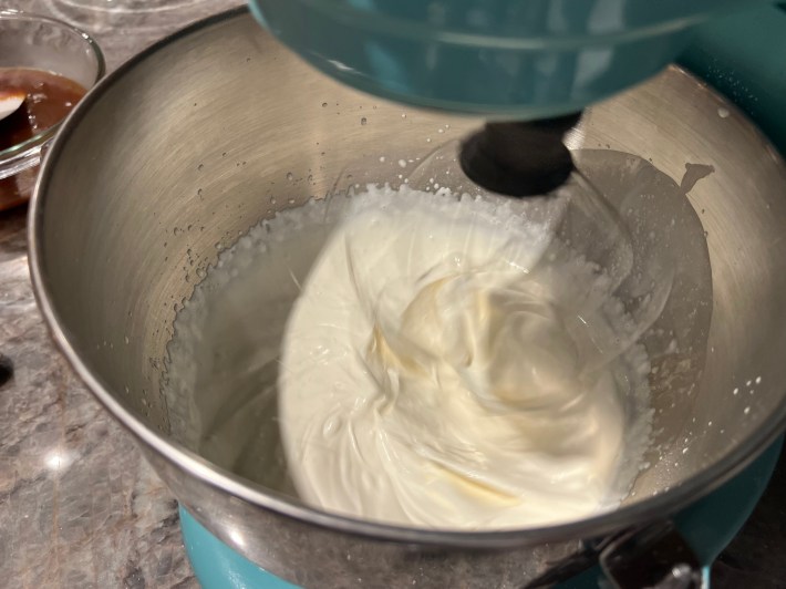 Cream, vanilla, and icing sugar whipping in a stand mixer.