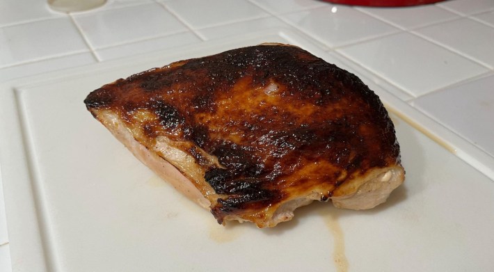 A roasted turkey breast on a cutting board. Its skin is dark and crispy.