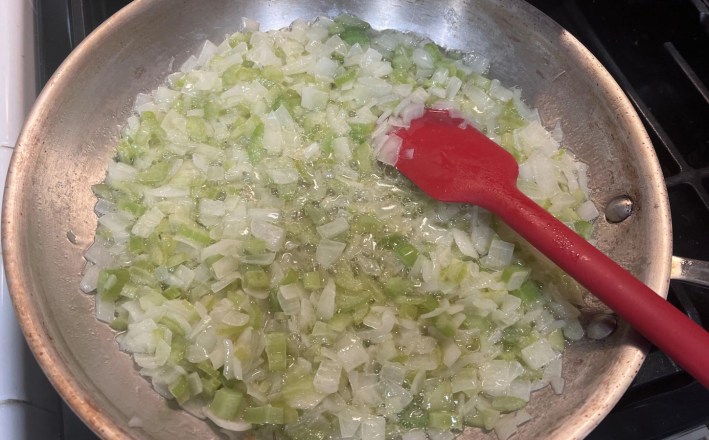 Diced onions and celery sweating in butter in a stainless steel pan.