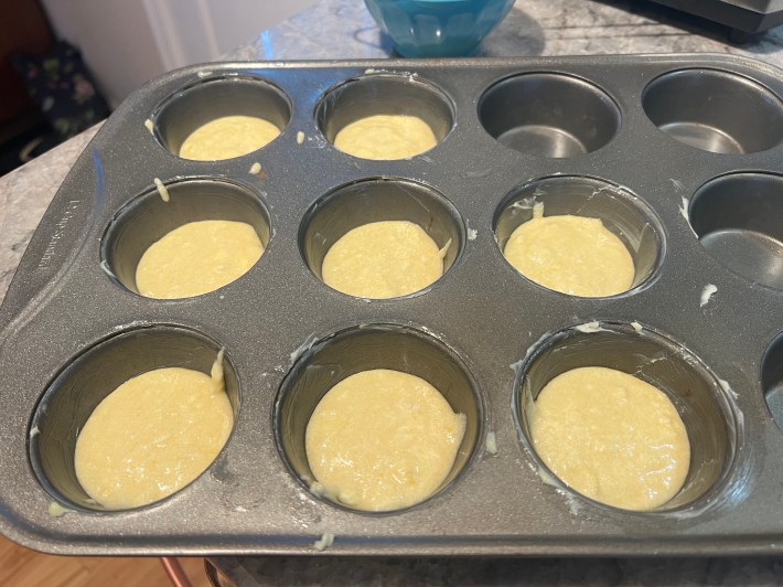 Sponge batter distributed into a muffin tin.