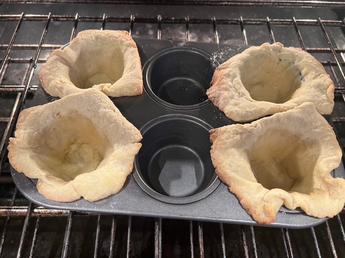 Four tart crusts, after 15 minutes of blind-baking in muffin cups.