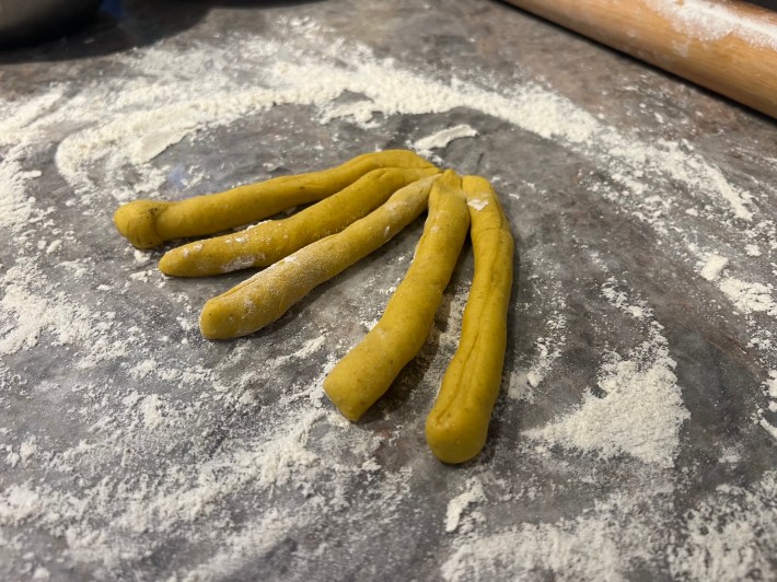 Five finger-length strands of bread dough, waiting to be braided.