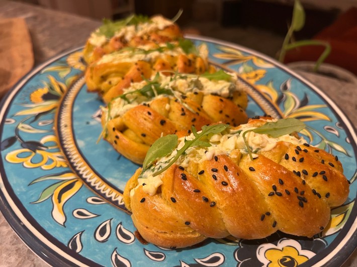 Plaited bread rolls, split down the middle and filled with egg-and-arugula salad.