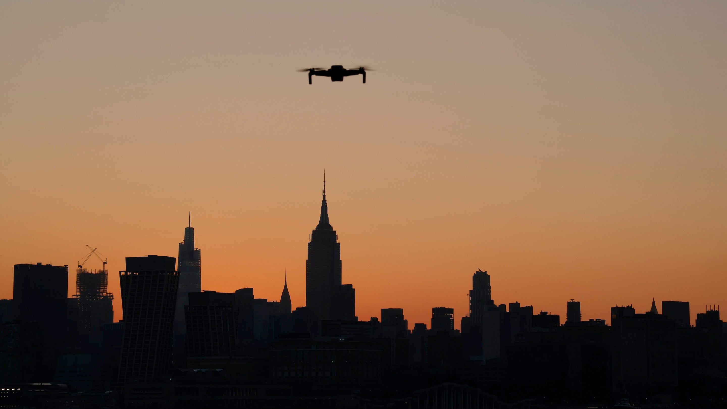 A small drone flies in front of the skyline of midtown Manhattan and the Empire State Building as the sun rises in New York City on August 11, 2023