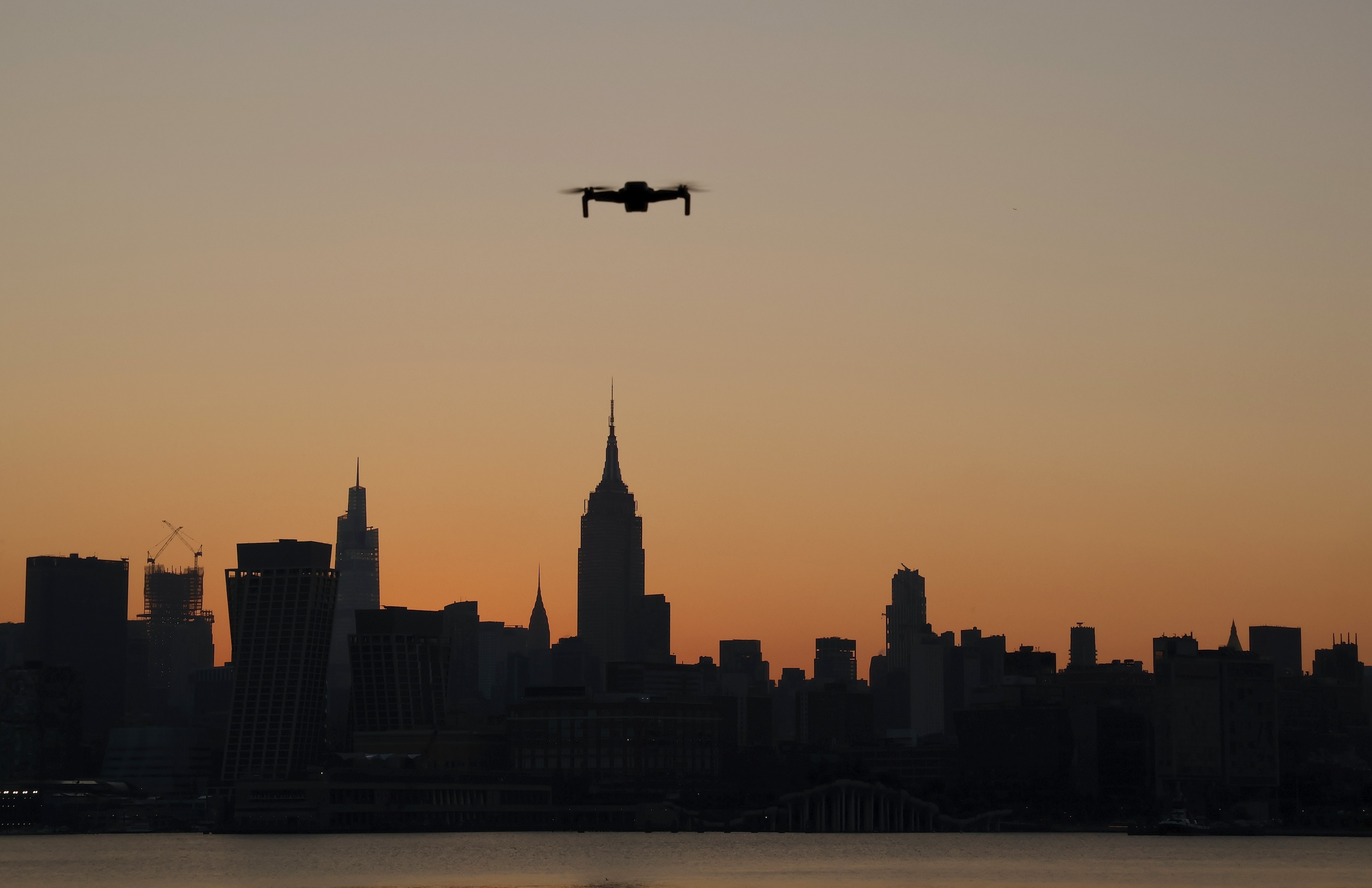 A small drone flies in front of the skyline of midtown Manhattan and the Empire State Building as the sun rises in New York City on August 11, 2023